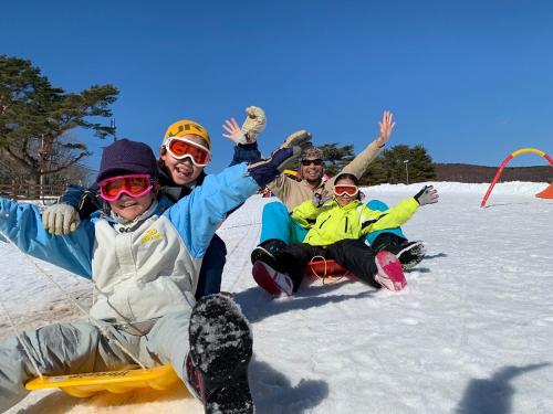 a group of people sitting in the snow on a sled at Mineyama Kogen Hotel Relaxia in Kamikawa