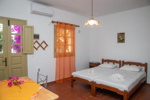 a bedroom with two beds and a table and a door at FLOWERS STUDIOS in Skala