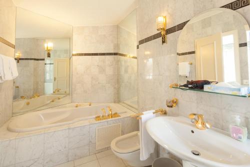 a bathroom with a tub and a toilet and a sink at Hotel Central Continental in Interlaken