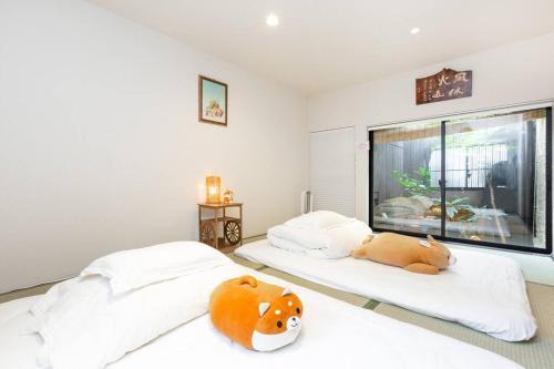 Dos camas con animales de peluche en un dormitorio en ゲストハウス至の宿 Shibainu-Themed Guesthouse en Kyoto