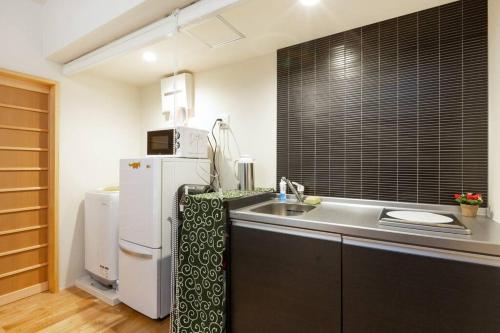 a small kitchen with a sink and a refrigerator at ゲストハウス至の宿 Shibainu-Themed Guesthouse in Kyoto