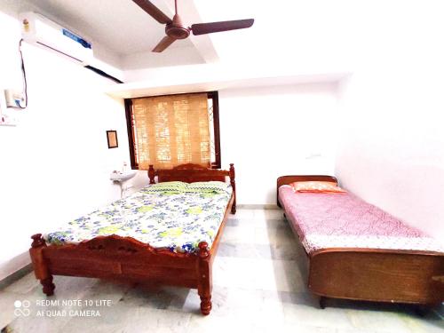 two beds in a room with a ceiling fan at Beach/US Russian Consulate/Kitchen/Unlimited Super Fast Wifi in Chennai