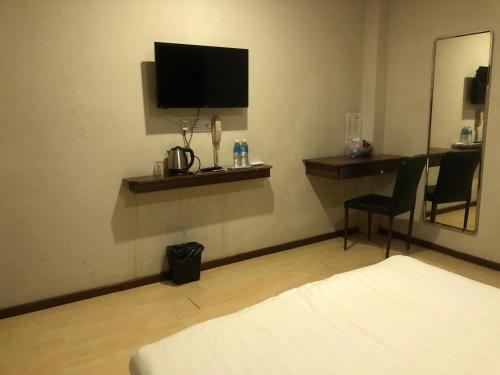 a hotel room with a bed and a desk and a television at Super OYO 90668 Joy Inn in Miri