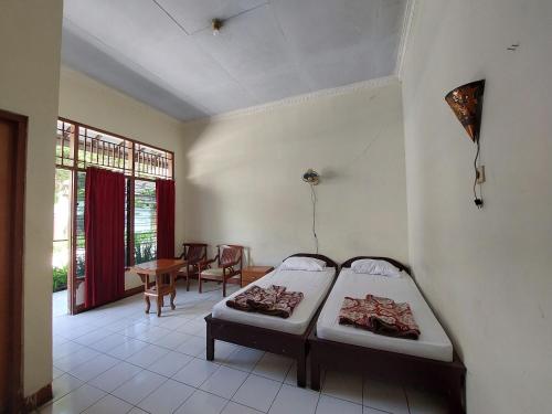 a room with two beds and a dining room with a table at Puri Merbabu Asri 