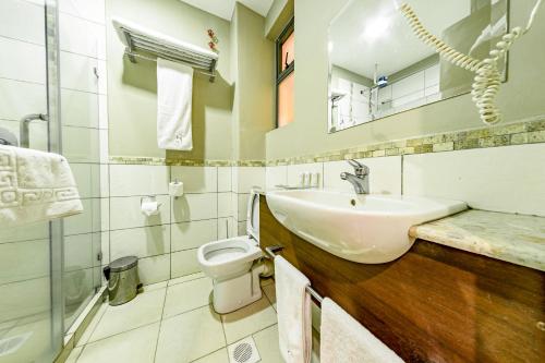 a bathroom with a sink and a toilet and a mirror at Hotel Rio in Nairobi