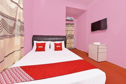 a bedroom with a bed with red pillows and a tv at Capital O 90664 Rabi Hotel in Kota Bharu