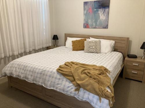 um quarto com uma cama com um cobertor em SummerBreeze - just a 60 second stroll to the beach em Culburra Beach
