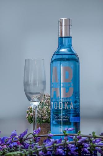 a bottle of vodka next to a glass and purple flowers at The Breeze Luxury Apartment in Nuwara Eliya