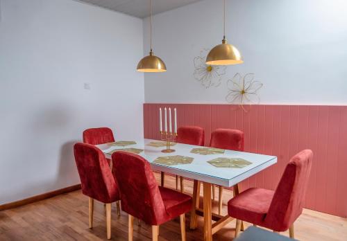a dining room with a table and red chairs at The Breeze Luxury Apartment in Nuwara Eliya
