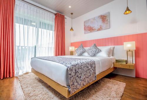 a bedroom with a large bed with red curtains at The Breeze Luxury Apartment in Nuwara Eliya