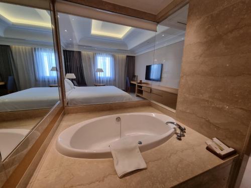 a bathroom with a bath tub and a large mirror at Pinegrove Hotel in Gimhae