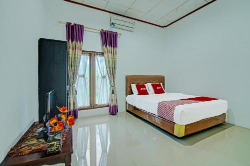 a bedroom with a bed and a table with flowers at OYO 91852 Prima Guesthouse Syariah in Padang