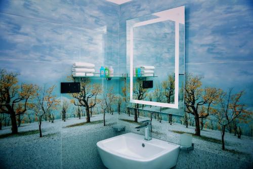 a bathroom with a mirror and a sink and trees at Aurum Boutique in Negombo