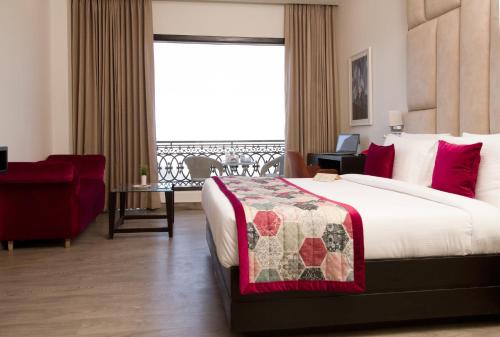 a hotel room with a bed and a red chair at Rosetum Kasauli in Kasauli