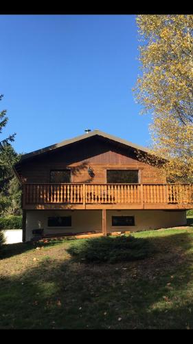 a large wooden house with a deck on a field at Gite de Montagne "Calluna" 1 ou 2 pers in Xonrupt-Longemer