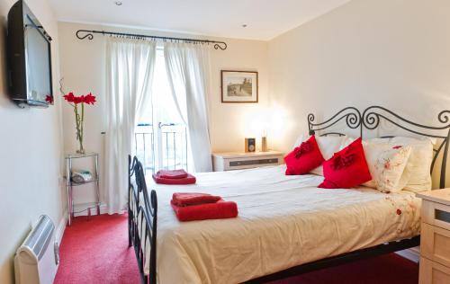 a bedroom with a large bed with red pillows at Watermark Apartments in Whitby