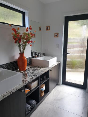 a bathroom with a sink and a vase of flowers on a counter at Garden View Cottages in Picton