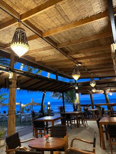 a restaurant with tables and chairs and a view of the ocean at Noble House Beach Resort in Ko Lanta