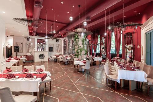 a restaurant with white tables and chairs and red walls at Ivy Garden Hotel Baku in Baku