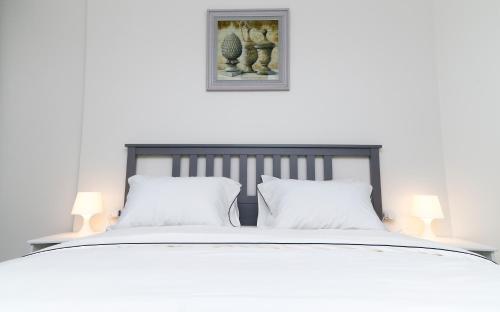 een wit bed met 2 witte kussens en 2 lampen bij Porto Said Resort Rentals in `Ezbet Shalabi el-Rûdi