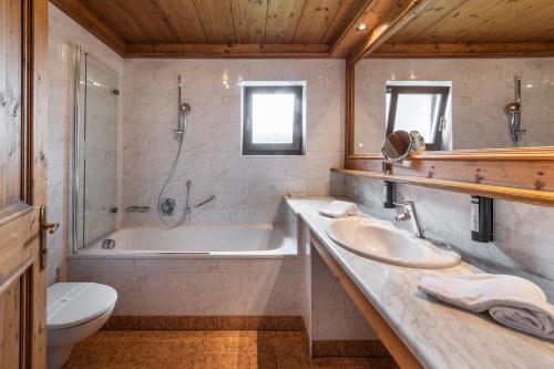 a bathroom with a tub and a sink and a toilet at Romantik Hotel Santer in Dobbiaco