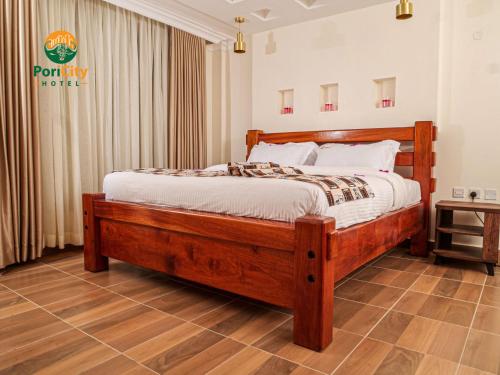 ein Schlafzimmer mit einem Holzbett in einem Zimmer in der Unterkunft Pori City Hotel in Nairobi