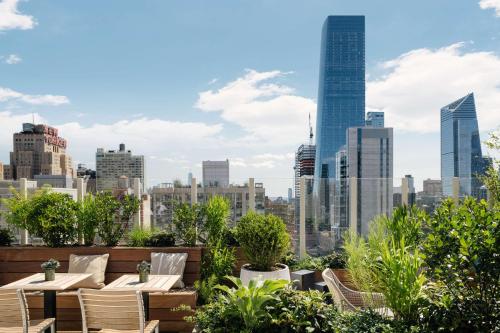 um pátio no último piso com mesas e cadeiras e um horizonte da cidade em Arlo Midtown em Nova York