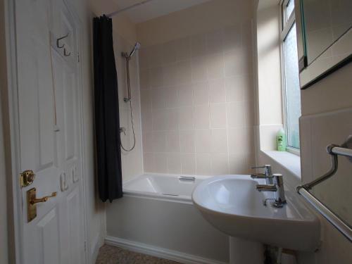 La salle de bains est pourvue d'une baignoire, d'un lavabo et d'une douche. dans l'établissement Lovely 2 bedroom apartment located near Newcastle., à Longbenton
