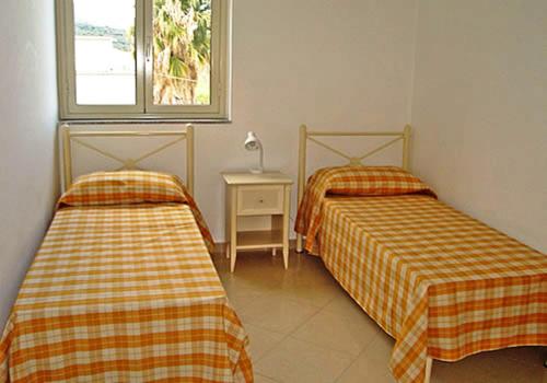 a room with two beds and a table with a window at Appartamenti Pirrera in Patti