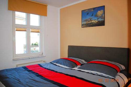 Schlafzimmer mit einem Bett mit blauer und roter Bettwäsche in der Unterkunft Miramar App. 14 in Ahlbeck