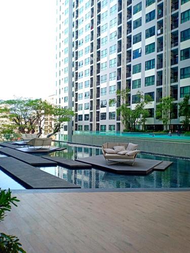 a row of lounge chairs in a pool with buildings at The Base Horizon Central Pattaya in Pattaya