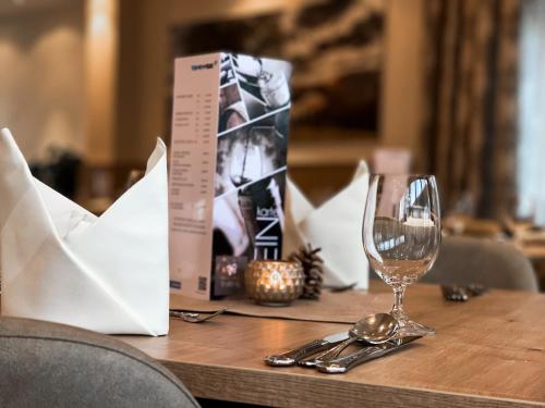 a wooden table with a glass of wine on it at Hotel Trattnig in Döbriach