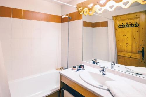 La salle de bains est pourvue d'un lavabo, d'une baignoire et d'un miroir. dans l'établissement Appartement cosy T3 4 à 6 pers avec Piscines Intérieure, Extérieure & Sauna à Samoëns en Haute-Savoie, à Samoëns