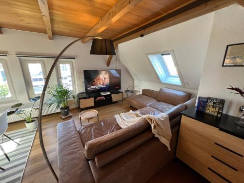 Una sala de estar con un sofá y un televisor de pantalla plana. en Wohlfühl Loft - Seenähe, Boxspringbett, Küche, en Bregenz