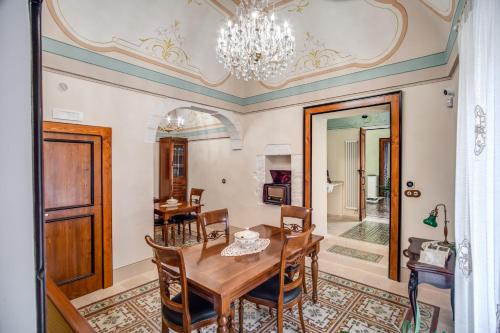 une salle à manger avec une table, des chaises et un lustre dans l'établissement Palazzo Stunis - Dimora di Charme, à Ostuni