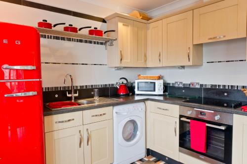 uma cozinha com um frigorífico vermelho e uma máquina de lavar roupa em Watermark Apartments em Whitby