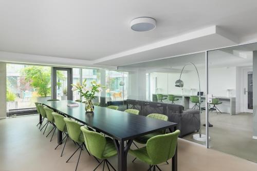 a dining room with a black table and green chairs at VISIONAPARTMENTS Basel - contactless check-in in Basel