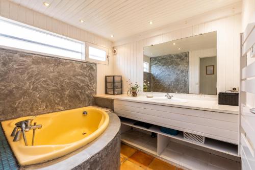 een badkamer met een geel bad en een grote spiegel bij Villa bleue in Sanguinet