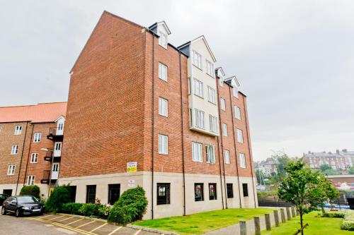 um grande edifício de tijolos com um carro estacionado ao lado em Watermark Apartments em Whitby