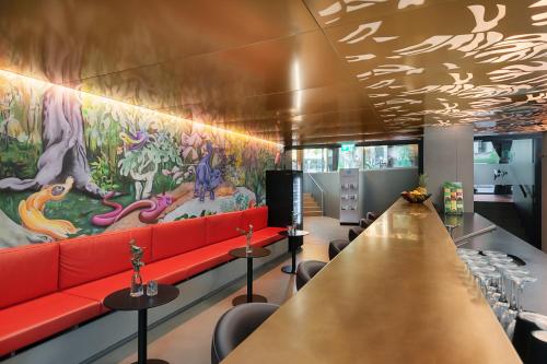 un bar con sofá rojo y un gran mural en VISIONAPARTMENTS Basel Nauenstrasse - contactless check-in en Basilea