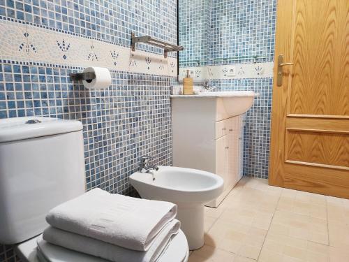 Baño de azulejos azules con aseo y lavamanos en AC Apartaments Pleta Soldeu, en Soldeu