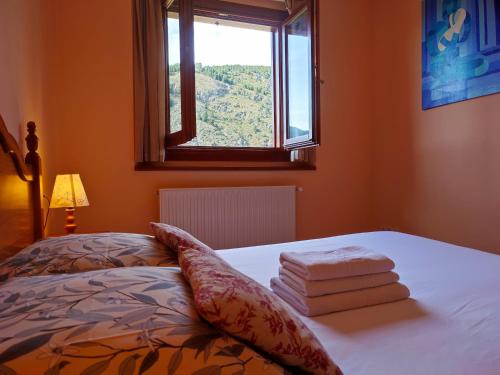 a bedroom with a bed with a window and some towels at AC Apartaments Pleta Soldeu in Soldeu