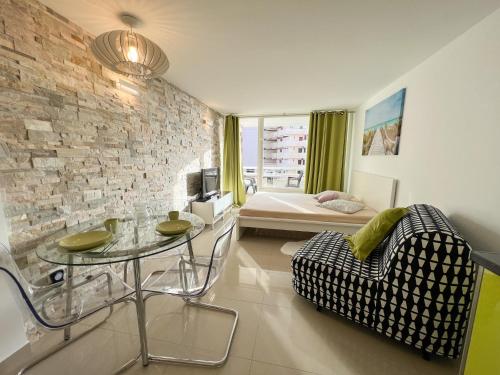 a living room with a glass table and a bed at Studioapartment Borinquen in Playa Fañabe