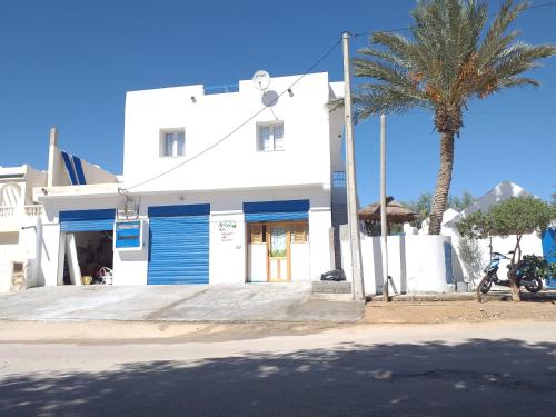 a white building with a palm tree in front of it at Dar Janis Djerba دار يانيس جربة in Houmt Souk