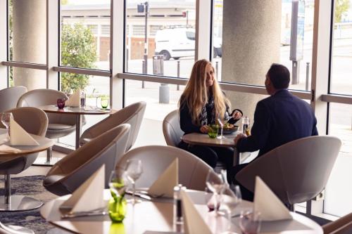 a man and woman sitting at tables in a restaurant at Mercure Paris Ivry Quai De Seine in Ivry-sur-Seine
