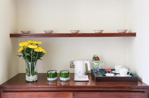 a wooden table with a vase of yellow flowers on it at Almanity Hoi An Resort & Spa in Hoi An