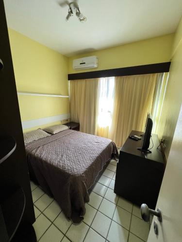um quarto com uma cama, uma secretária e uma televisão em Navegantes apartamento no Recife
