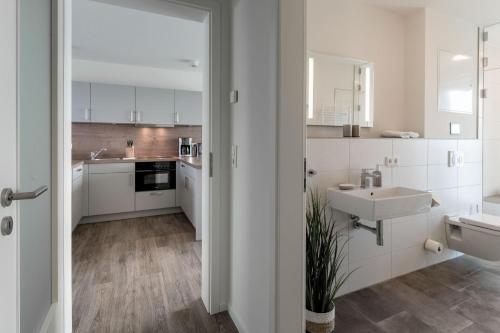 a white kitchen with white cabinets and a sink at Ferienwohnung Ankergold in Nordstrand
