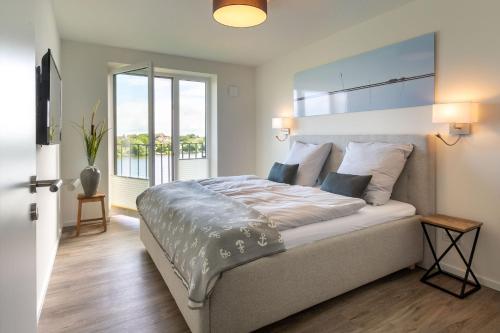 a bedroom with a large bed with a large window at Ferienwohnung Ankergold in Nordstrand