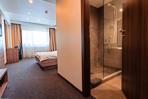 a hotel room with a shower and a bed at Hotel Oscar in Câmpina